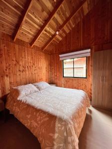 a bedroom with a bed in a wooden room at Cabañas Entre Árboles Pucón in Pucón