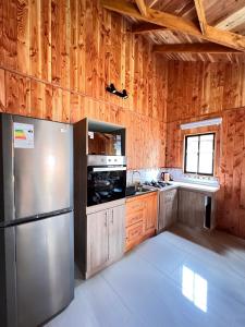 a kitchen with a stainless steel refrigerator and wooden walls at Cabañas Entre Árboles Pucón in Pucón