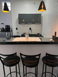 a kitchen with three chairs in front of a counter at Kitnet Cidade de Goiás - Go #02 in Goiás