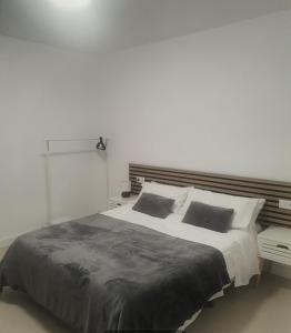 a white bedroom with a large bed with two pillows at Apartamento Gran Turia in Valencia