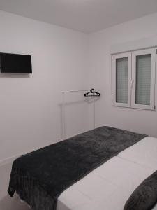 a white bedroom with a large bed with a window at Apartamento Gran Turia in Valencia