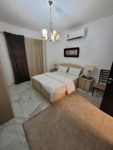 a bedroom with a large bed and a chandelier at رويال فيلا بمسبح خاص in King Abdullah Economic City