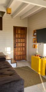 ein Wohnzimmer mit einem TV und einem gelben Tisch in der Unterkunft refugio vo olino in Imbituba