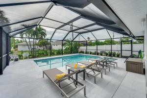 an indoor pool with tables and chairs and a swimming pool at Central Naples Home with Private Pool, Spa and Lanai! in Naples