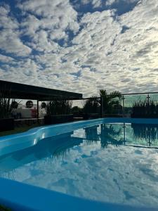 een blauw zwembad met een bewolkte hemel op de achtergrond bij Royal Madero Inn Express in Tampico