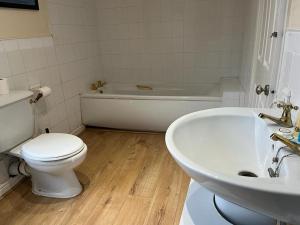 a bathroom with a toilet and a tub and a sink at Amazing Entire Home in Wolverhampton in Wolverhampton