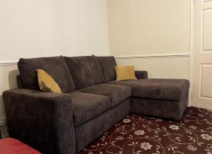 a brown couch with two yellow pillows in a living room at Amazing Entire Home in WOLVERHAMPTON in Wolverhampton