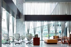 a lobby with chairs and a table and large windows at AC Hotel by Marriott Santa Fe in Mexico City