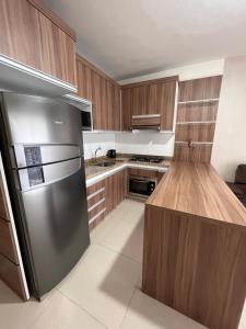 a kitchen with a stainless steel refrigerator and wooden cabinets at Casinha na praia in Imbé