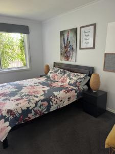 1 dormitorio con 1 cama con colcha de flores y ventana en Inner City Boutique Home. Pet and Family Friendly!, en Canberra