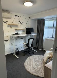 ein Büro mit einem Schreibtisch mit einem Computer und Fledermäusen an der Wand in der Unterkunft Inner City Boutique Home. Pet and Family Friendly! in Canberra