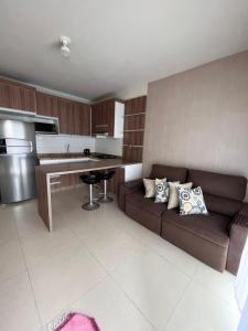 a living room with a brown couch in a kitchen at Casinha na praia in Imbé