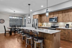 a kitchen with wooden cabinets and a bar with bar stools at Echo Landing #42 by Bear Country in Sun Peaks