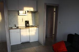 a small kitchen with white cabinets and a sink at Haus Nordsee 06 in Duhnen