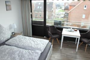 Schlafzimmer mit einem Bett, einem Tisch und einem Fenster in der Unterkunft Jan am Strand 315 in Cuxhaven