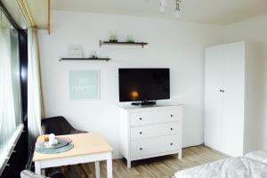 ein Wohnzimmer mit einem TV und einer weißen Kommode in der Unterkunft Jan am Strand 315 in Cuxhaven
