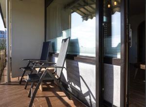 2 Stühle auf einem Balkon mit Blick aus dem Fenster in der Unterkunft Jan am Strand 315 in Cuxhaven