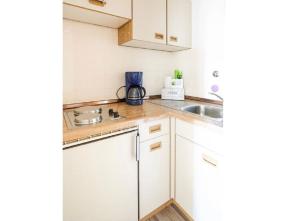 eine Küche mit weißen Schränken und einem Waschbecken in der Unterkunft Jan am Strand 315 in Cuxhaven