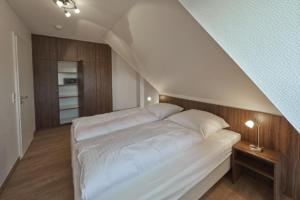 um quarto com uma grande cama branca num sótão em Op de Geest 15 em Cuxhaven