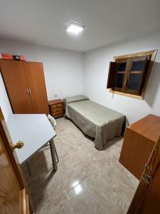 een slaapkamer met een bed, een bureau en een raam bij Casa Paula in Ceuta