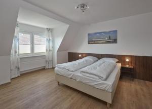 een slaapkamer met een groot bed met witte lakens bij Op de Geest 16 in Cuxhaven