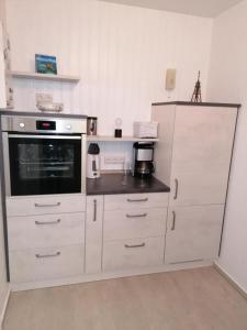 a kitchen with white cabinets and a microwave at Haus Kehrwieder Fewo 03 in Cuxhaven