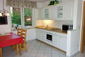 a kitchen with white cabinets and a table with a red table at Padua 4A in Duhnen