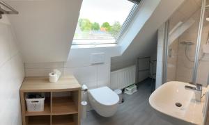 a bathroom with a toilet and a sink and a window at Haus Muschelnest in Sahlenburg