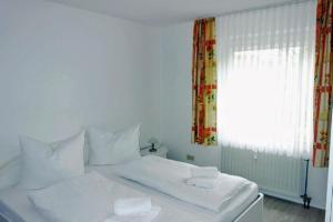 uma cama branca com duas almofadas brancas e uma janela em Gorch Fock 04 em Duhnen
