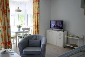 uma sala de estar com uma cadeira e uma televisão em Gorch Fock 04 em Duhnen
