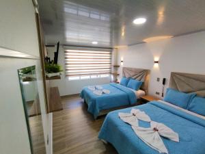 ein Hotelzimmer mit 2 Betten und einem Fenster in der Unterkunft Hotel Casa Baquero in Bogotá