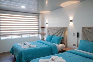 a bedroom with two beds with blue sheets and a window at Hotel Casa Baquero in Bogotá