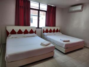 2 camas en una habitación con cortinas rojas en Minshu RoomStay en Arau