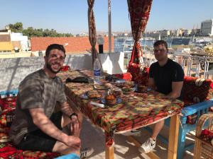 Twee mannen aan een tafel met eten erop. bij Gamal Robob Nubian Guest House in Aswan