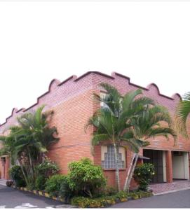 ein Backsteingebäude mit Palmen davor in der Unterkunft Aparta Hotel Plenitud in Palmira
