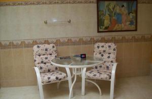 帕爾米拉的住宿－Aparta Hotel Plenitud，两把椅子和一张桌子以及一张桌子和椅子