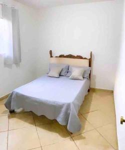 1 dormitorio con 1 cama blanca y 2 almohadas en Casa na Orla de Lagoa Santa, en Lagoa Santa