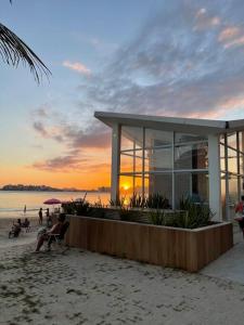 um edifício na praia com o pôr-do-sol ao fundo em Apt de luxo na Praia do Morro c/ vista para o mar em Guarapari