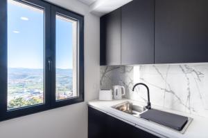 eine Küche mit schwarzen Schränken, einem Waschbecken und einem Fenster in der Unterkunft Apartamentos do Mercado in Covilhã