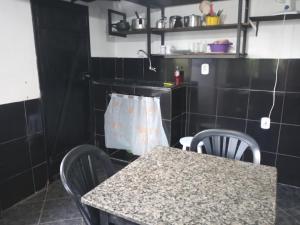 a table and chairs in a kitchen with black tiles at Calango's Beach-House-Arraial do Cabo in Arraial do Cabo