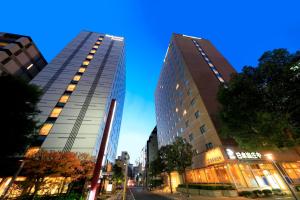 deux grands bâtiments sur une rue de la ville la nuit dans l'établissement Richmond Hotel Utsunomiya-ekimae, à Utsunomiya