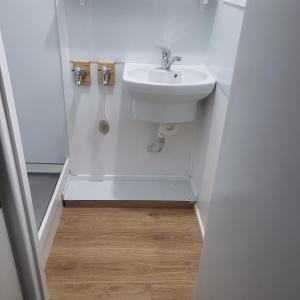 a bathroom with a white sink and a wooden floor at Huriana Place in Kaitaia