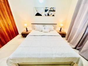 a large white bed in a room with two lamps at Stay at Al Ghaimah Holiday Homes 1 Bedroom Apartment Near Airport in Dubai