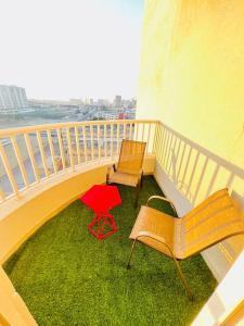 two chairs and a red table on a balcony at Stay at Al Ghaimah Holiday Homes 1 Bedroom Apartment Near Airport in Dubai