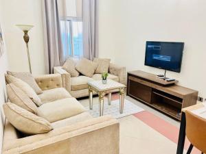 a living room with two couches and a flat screen tv at Stay at Al Ghaimah Holiday Homes 1 Bedroom Apartment Near Airport in Dubai