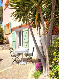 two chairs and a house with two palm trees at L'Excursion - Charmant T2 Rénové proche de la mer in Cassis