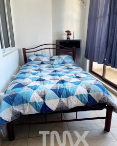 a bed with a blue and white quilt on it at TMX HOSTAL in Puerto Escondido