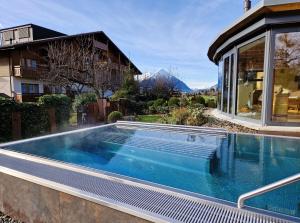 a swimming pool in front of a house at SALZANO Apartments in Interlaken