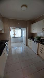 a kitchen with white cabinets and a large tile floor at Paim Maria in Ponta Delgada