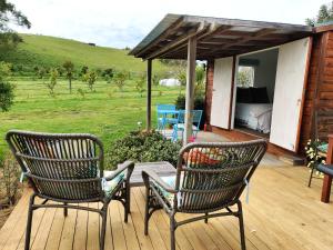 2 Stühle und ein Tisch auf einer Holzterrasse in der Unterkunft Haumoana Herb Cottage in Haumoana